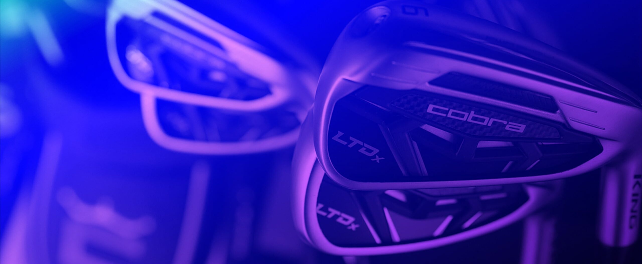 Close-up of Cobra LTDx golf clubs with a blue and purple lighting effect.