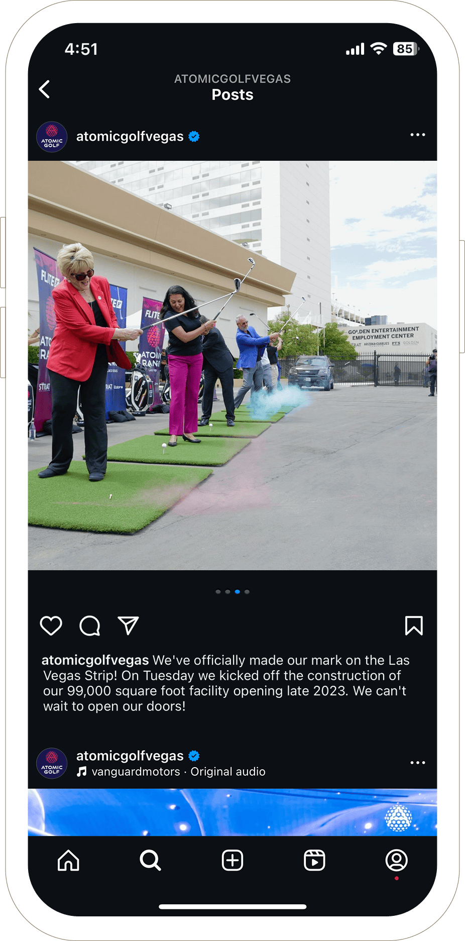 Three people swing golf clubs at an outdoor event with a city building in the background.