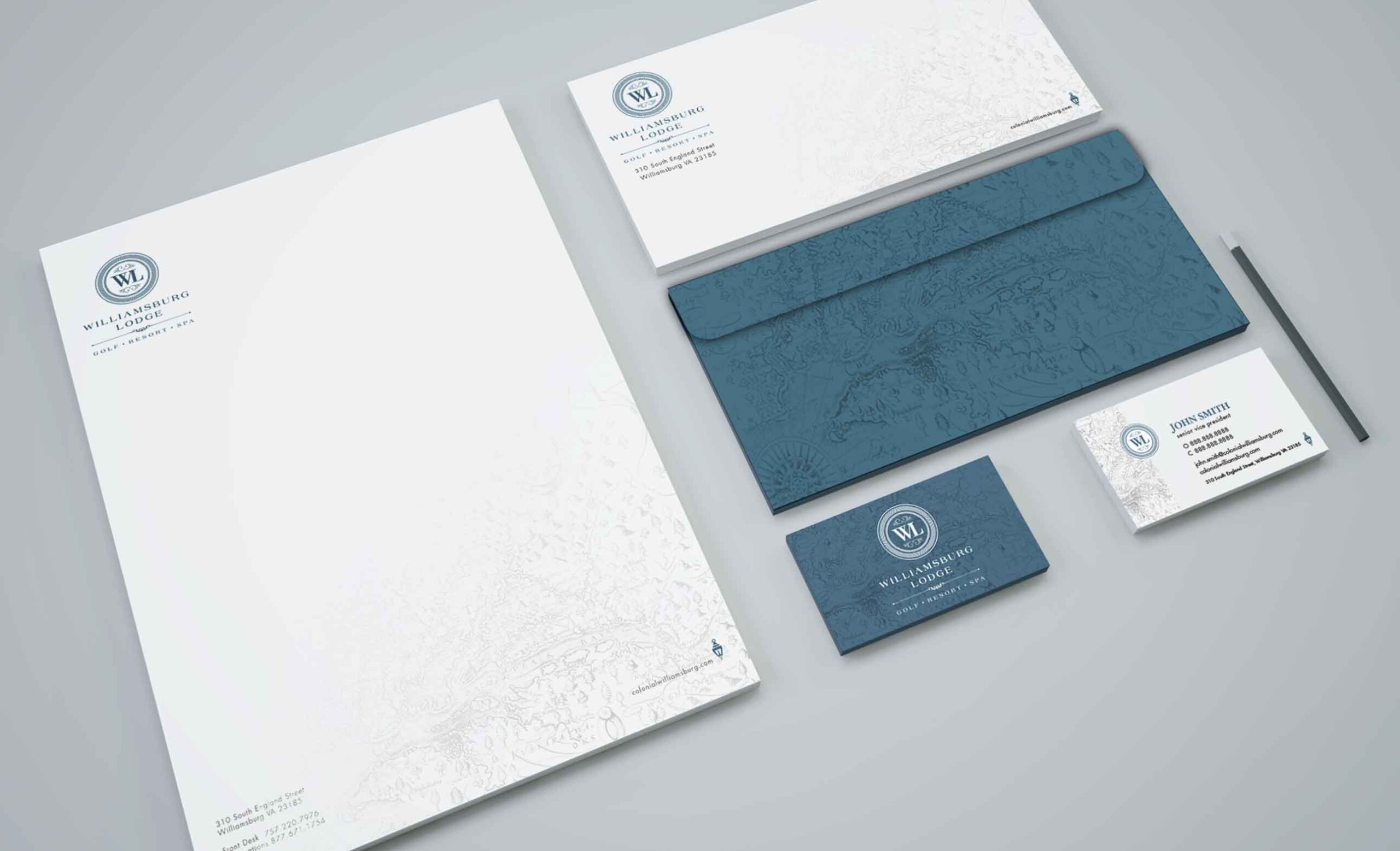 Branded stationery set with letterhead, envelopes, business cards, and a pen in white and blue design.