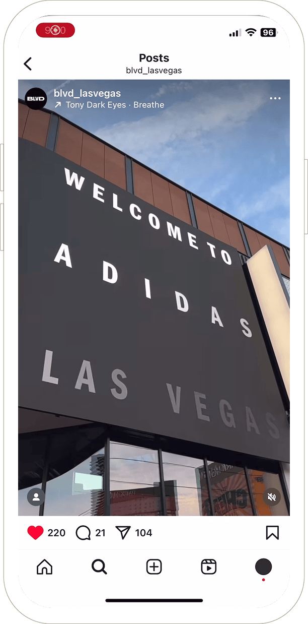 Large black sign on a building reads WELCOME TO ADIDAS LAS VEGAS against a blue sky.