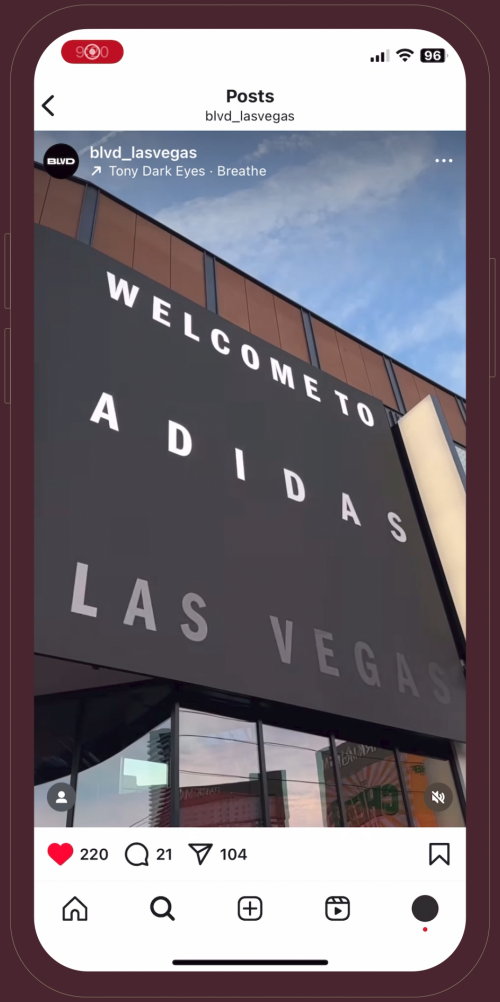 Large black Adidas Las Vegas store sign with bold white letters, viewed from below against a blue sky.