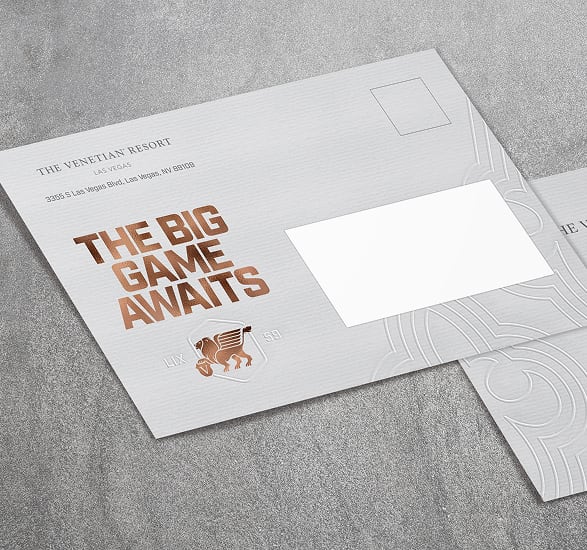 Envelope with The Big Game Awaits in bold text and a small winged lion graphic, on a textured surface.